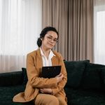 Confident woman in business attire sits on a sofa, exuding professionalism.